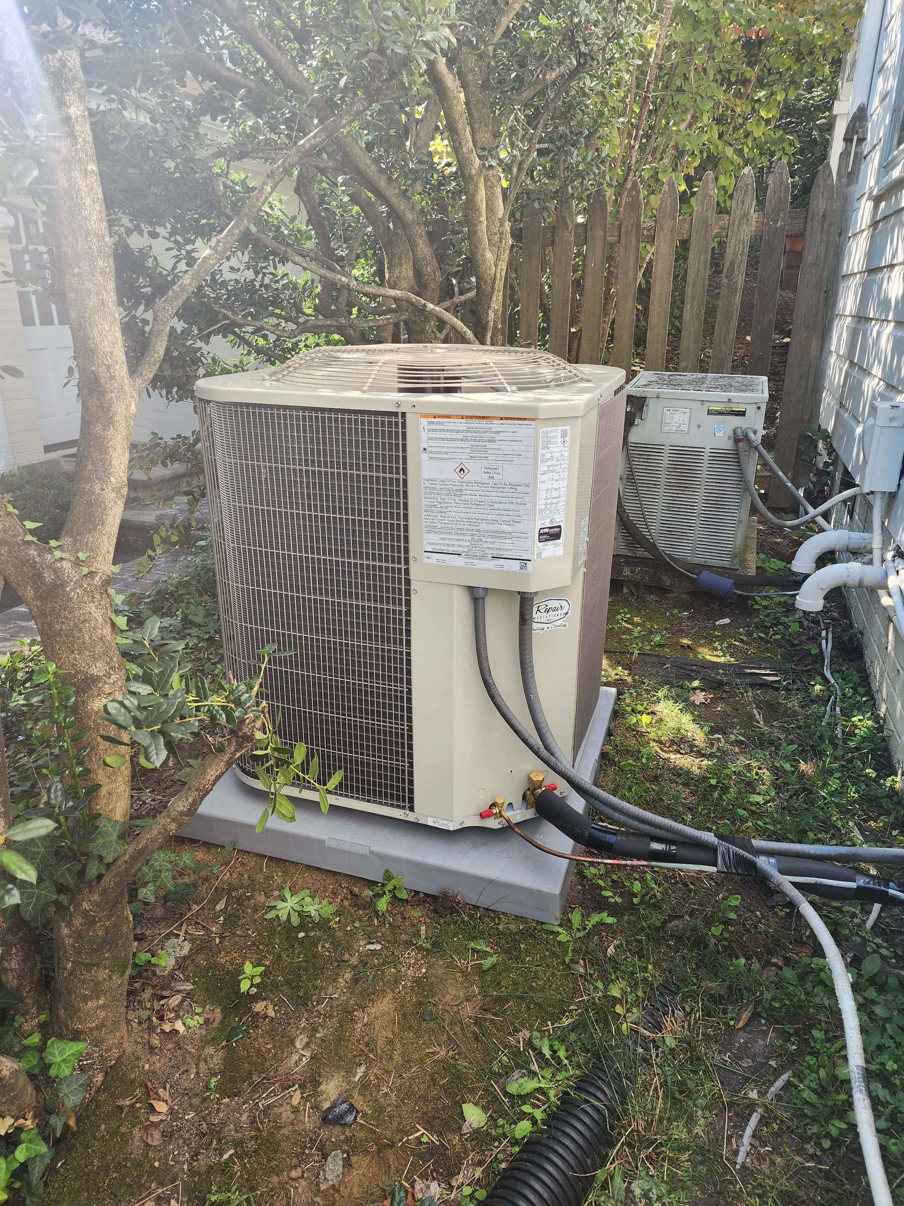 Heat pump outdoor unit installed on concrete pad with refrigerant lines and electrical connections